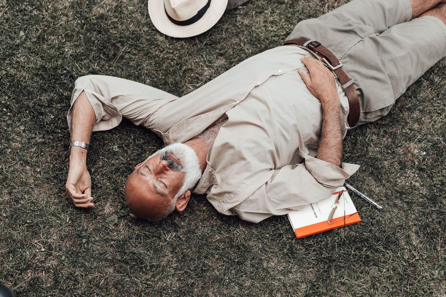 Indépendant d'un certain âge, détendu dans l'herbe, lunettes et carnet de notes posés à côté de lui : le repos que permet une pension complémentaire bien préparée